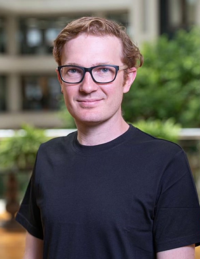 Henry wearing a black T-shirt with greenery in the background